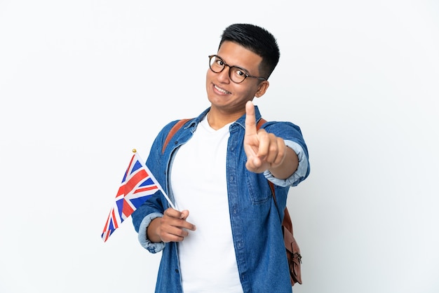 Young Ecuadorian woman holding an United Kingdom flag isolated on white wall showing and lifting a finger