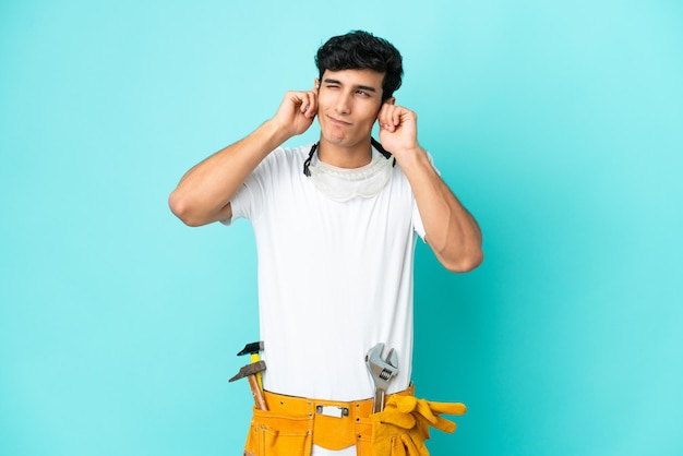 Young electrician Argentinian man isolated on blue background frustrated and covering ears