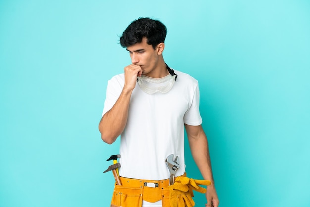 Young electrician Argentinian man isolated on blue background having doubts