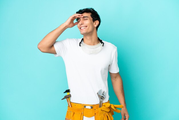 Young electrician Argentinian man isolated on blue background smiling a lot