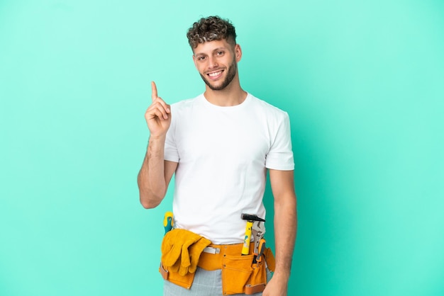 Young electrician blonde man isolated on green background showing and lifting a finger in sign of the best