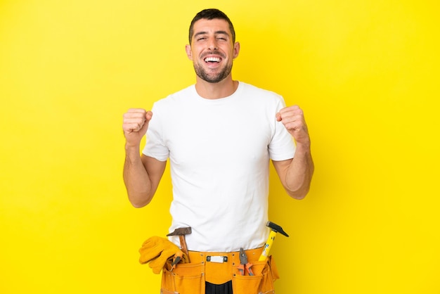 Young electrician caucasian man isolated on yellow background celebrating a victory in winner position