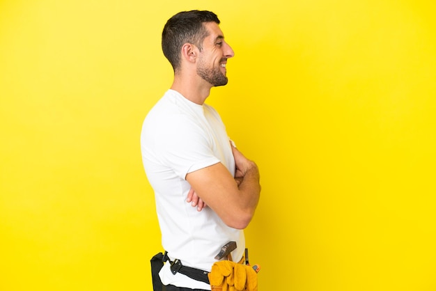Young electrician caucasian man isolated on yellow background in lateral position