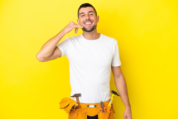 Young electrician caucasian man isolated on yellow background making phone gesture Call me back sign