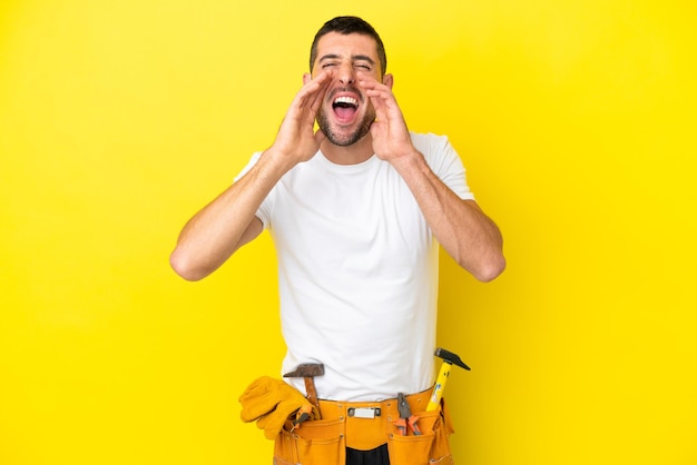 Young electrician caucasian man isolated on yellow background shouting and announcing something