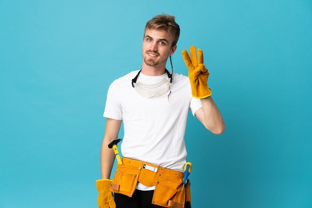 Young electrician man isolated wall happy and counting three with fingers