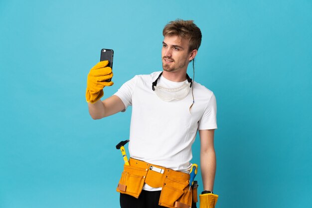 Young electrician man over isolated wall making a selfie