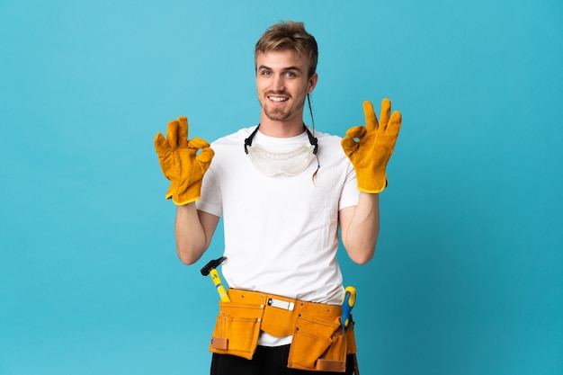 Young electrician man on isolated wall showing an ok sign with fingers