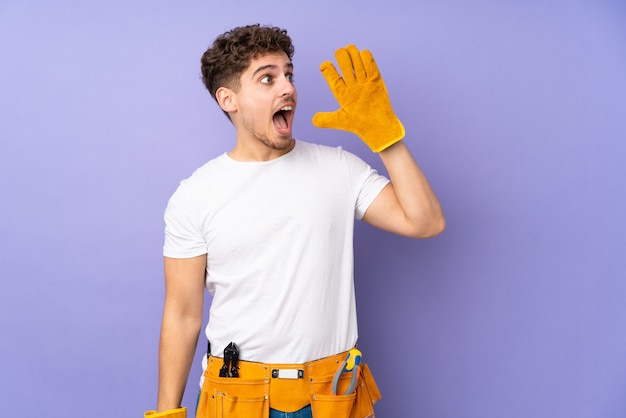 Young electrician man over isolated wall