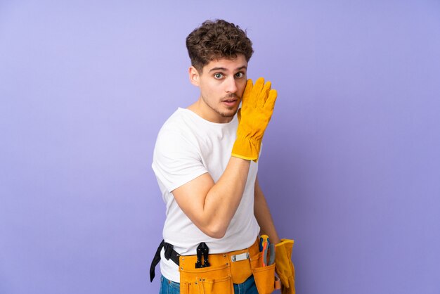 Young electrician man over on purple wall whispering something