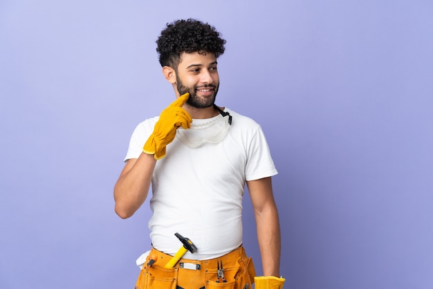 Young electrician Moroccan man isolated on purple thinking an idea while looking up