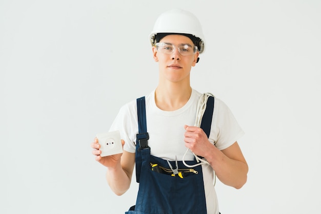 Young electrician on white wall