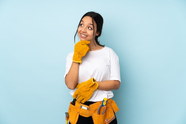 Young electrician woman on blue looking to the side