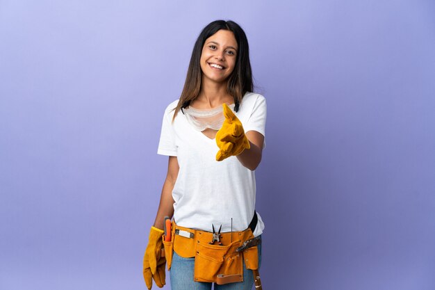 Young electrician woman isolated on purple shaking hands for closing a good deal