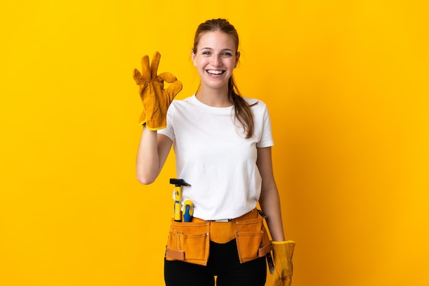 Young electrician woman isolated on yellow background showing ok sign with fingers