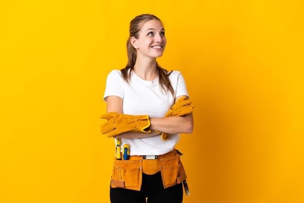 Young electrician woman isolated on yellow looking up while smiling