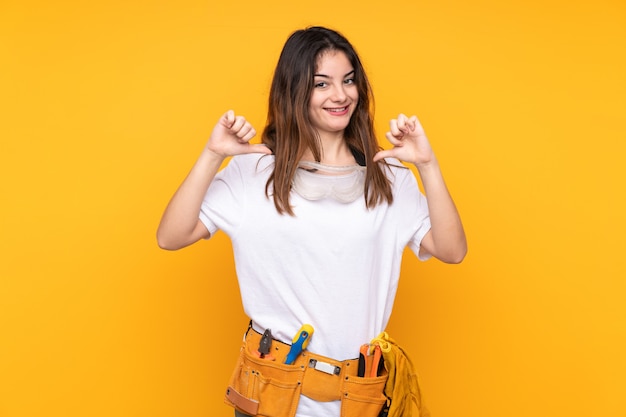 Young electrician woman over isolated on yellow proud and self-satisfied