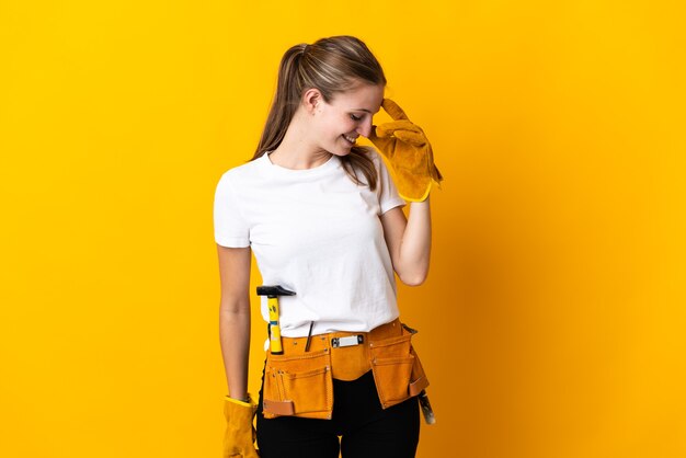 Young electrician woman isolated on yellow wall laughing