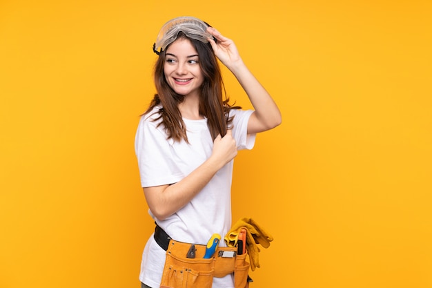 Young electrician woman over on yellow wall