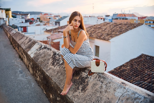 Young elegant barefoot woman posing on the street.