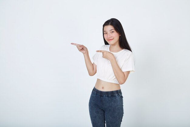 Young elegant beautiful Asian woman smiling and pointing finger away at copy space