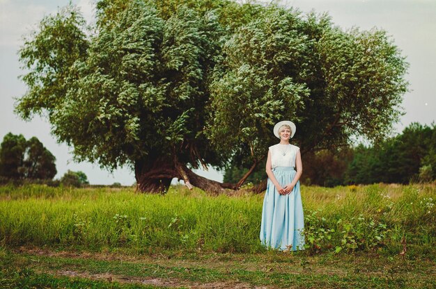 Young elegant happy woman in white hat in the field walking, smiling. Vintage clothes. Autumn season