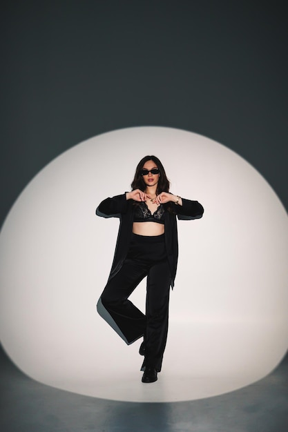 Young elegant stylish woman in a black suit Studio shot A woman in a black suit and black glasses on a white background