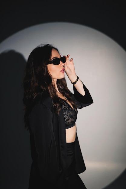 Young elegant stylish woman in a black suit Studio shot A woman in a black suit and black glasses on a white background