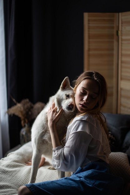 A young elegant tender woman loves her pet dog white albino Husky breed Girl hugs her fluffy dog