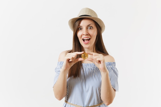 Young elegant woman in blue dress, hat with long hair holding bitcoin coin of golden color isolated on white background. Finance, business online virtual currency concept. Advertising area. Copy space