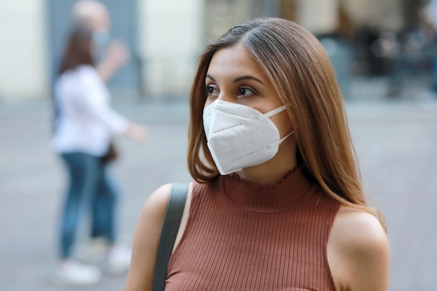 Giovane donna elegante in via della città che indossa la maschera protettiva kn95 ffp2