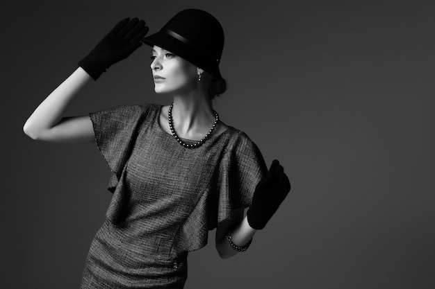 Young elegant woman, retro fashion, hat, gloves, dress. Black and white image.