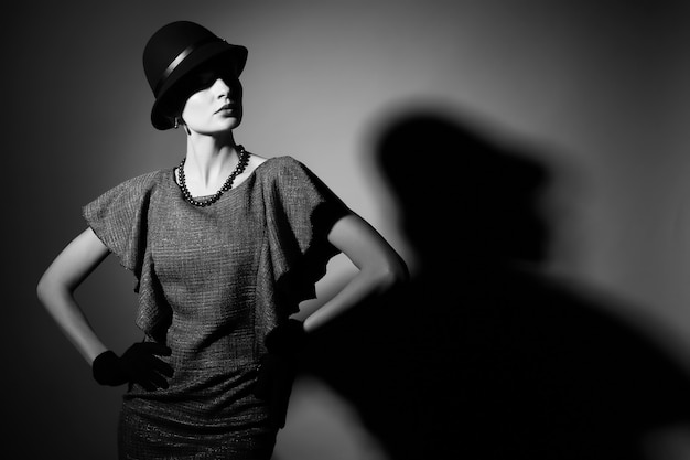 Young elegant woman, retro fashion, hat, gloves, dress. Black and white image.