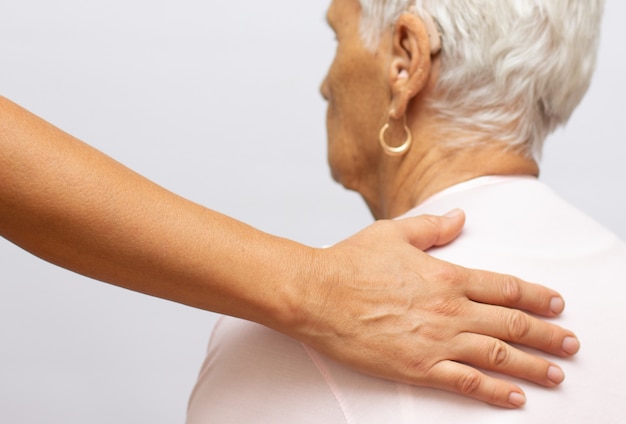 La mano della giovane donna elegante sulla spalla della signora anziana. ritratto di una vecchia signora sorridente con le mani della sua infermiera sulle spalle. segno di prendersi cura degli anziani. aiutare le mani. cura per il concetto di anziani.