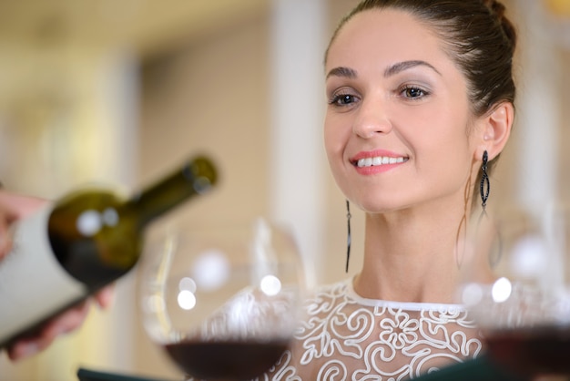 ワインのグラスを待っている若い上品な女性。