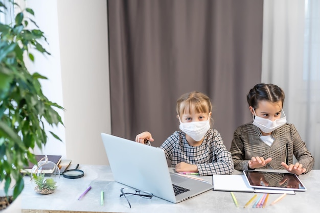 Фото Молодые девушки начальной школы с защитной маской для лица смотрят онлайн-класс образования. образовательная концепция изоляции коронавируса или covid-19.