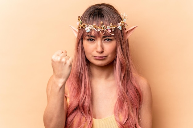 Photo young elf woman with pink hair isolated on beige background showing fist to camera aggressive facial expression