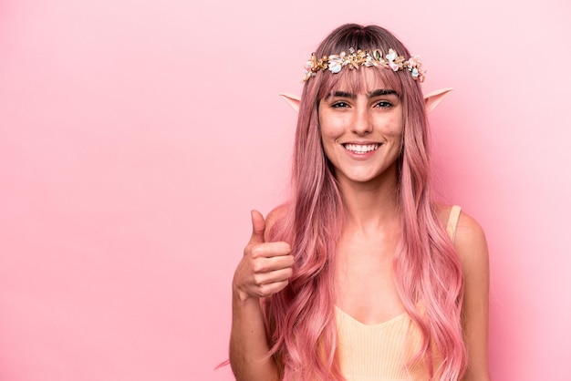 Young elf woman with pink hair isolated on pink background smiling and raising thumb up