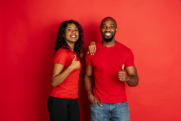 Young emotional african-american man and woman on red