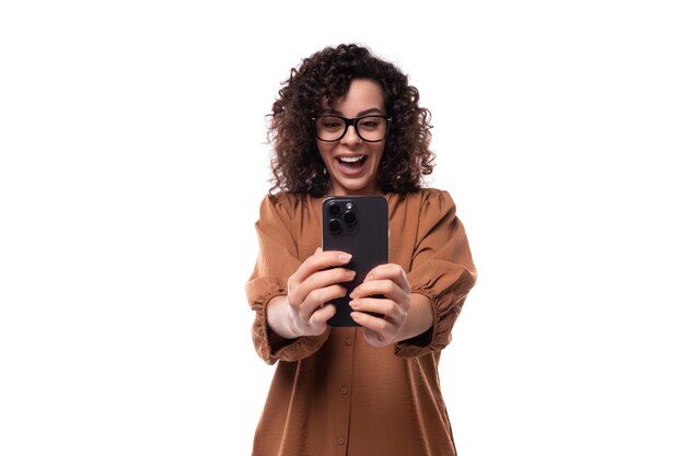 Young emotional curly leader woman in a brown shirt makes a photo on the phone