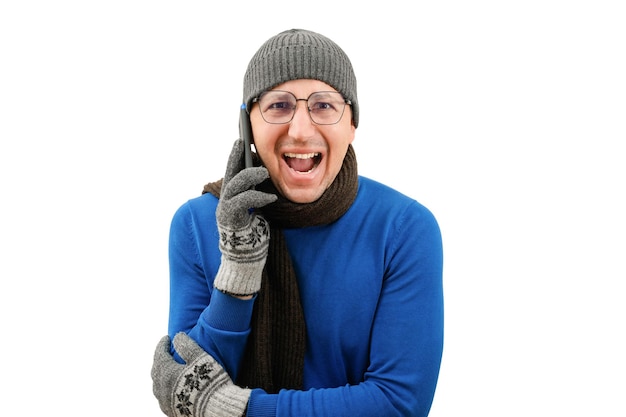 A young emotional man in warm clothes with a phone in his hands on a white background