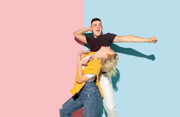 Young emotional man and woman on pink and blue background