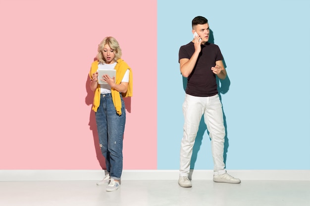 Young emotional man and woman on pink and blue background