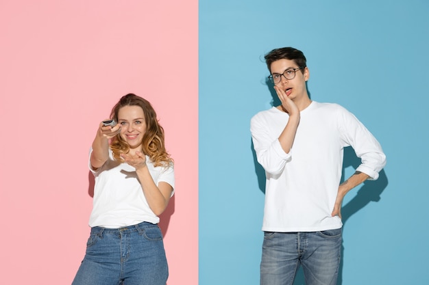 Young emotional man and woman on pink and blue background