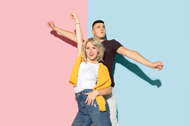 Photo young emotional man and woman on pink and blue background