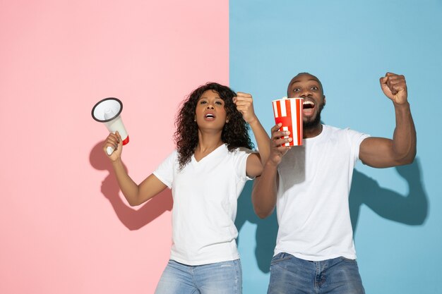 Young emotional man and woman on pink and blue background