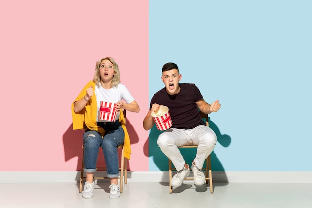 Young emotional man and woman on pink and blue background