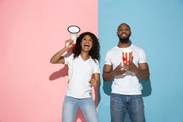 Young emotional man and woman on pink and blue background