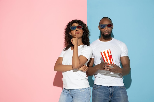 Young emotional man and woman on pink and blue background