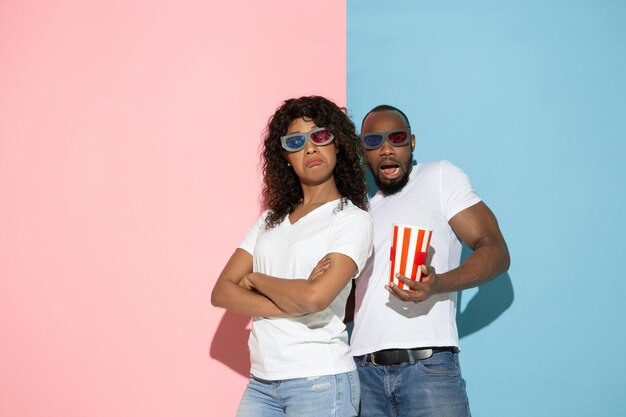 Young emotional man and woman on pink and blue background